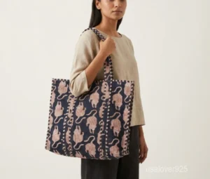 Close-up of the exotic jungle print detailing, dense parallel line quilted stitching rows, wide horizon profile, and comfortable 13-inch handles on an Indian cotton tote bag.