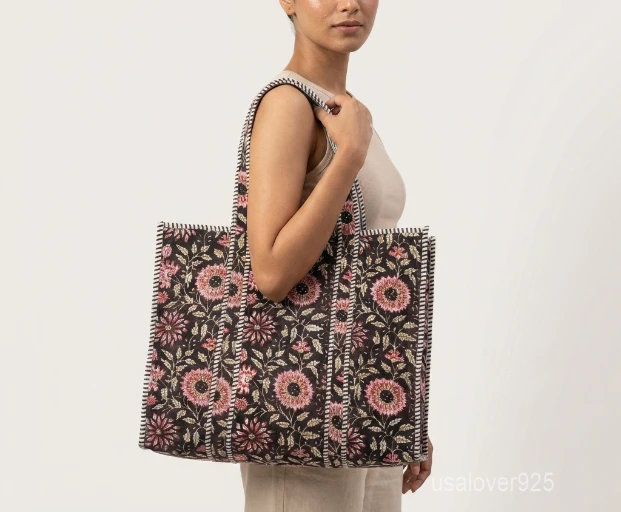 Close-up of the black block print detailing, dense parallel line quilted stitching rows, recycled cotton lining, and comfortable shoulder handles on an Indian cotton tote bag.