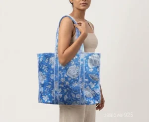 Close-up of the traditional hand block print detailing, dense parallel line quilted stitching rows, extra wide 25-inch high capacity layout, and comfortable handles on an Indian cotton tote bag.