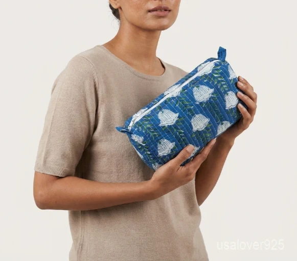 Close-up of the handcrafted blue print detailing, dense horizontal quilted stitching rows, waterproof internal plastic lining, elegant beads, and handcrafted tassel on an Indian cotton cosmetic pouch caddy.