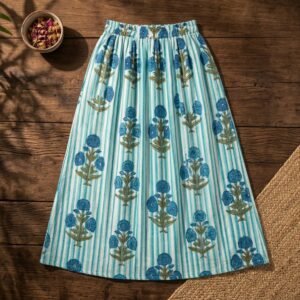 Close-up of the handcrafted blue botanical blossom print detailing, striped pattern accents, soft cotton fabric texture, and gathered waist layers on an Indian cotton midi skirt.