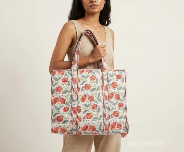 Close-up of the indigo botanical floral print, dense parallel line quilted stitching, and comfortable 11-inch strap drop handles on an Indian cotton shopper bag.
