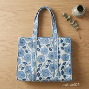 A person carrying a Blue Floral Quilted Cotton Tote Bag comfortably over their shoulder during a casual outdoor market run.