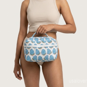 A traveler retrieving the Blue Strawberry Makeup Case from an overnight duffle bag, displaying its soft structure and vibrant cottagecore aesthetic style.