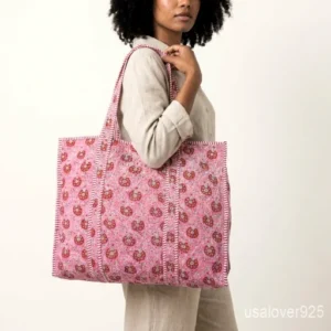 Close-up of the detailed embroidery accents, dense parallel line quilted stitching rows, contrast striped interior lining, inner slip pocket, and handles on an Indian cotton tote bag.