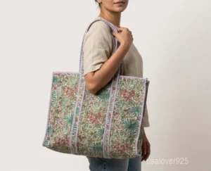 Close-up of the elegant block print detailing, dense parallel line quilted stitching rows, and comfortable 13-inch shoulder handles on an Indian cotton tote bag.