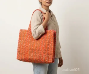 Close-up of the delicate floral prints, dense parallel line quilted stitching rows, and comfortable 13-inch extended shoulder handles on an Indian cotton shopper bag.