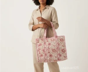 Close-up of the handprinted floral print detailing, dense parallel line quilted stitching rows, soft cotton interior, and comfortable shoulder handles on an Indian cotton tote bag.
