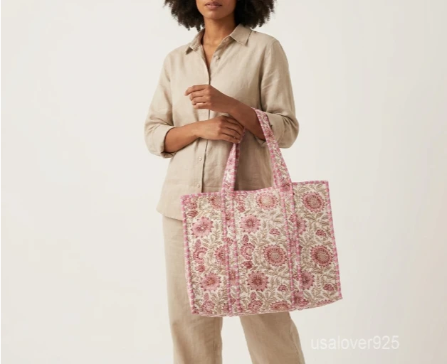 Close-up of the handprinted floral print detailing, dense parallel line quilted stitching rows, soft cotton interior, and comfortable shoulder handles on an Indian cotton tote bag.