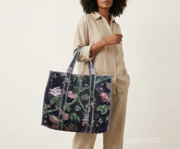 Close-up of the botanical block print detailing, dense parallel line quilted stitching rows, wide horizon profile layout, and comfortable handles on an Indian cotton tote bag.