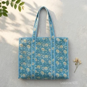 A person carrying a large Floral Print Quilted Cotton Tote Bag comfortably over their shoulder during an outdoor weekend market run.