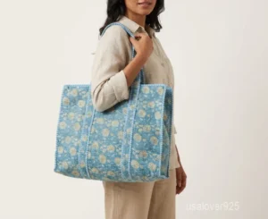 Close-up of the regional hand block print detailing, dense parallel line quilted stitching rows, extra-wide 7-inch deep bottom gusset base, and comfortable handles on an Indian cotton tote bag.