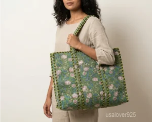 Close-up of the green and pastel flower print, dense parallel line quilted stitching, and comfortable padded shoulder straps on an Indian cotton shopper bag.
