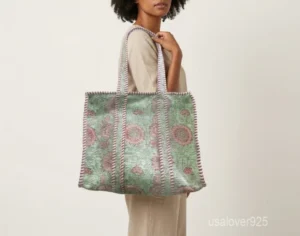 Close-up of the fresh green leaf prints, dense parallel line quilted stitching rows, and comfortable reinforced shoulder handles on an Indian cotton shopper bag.