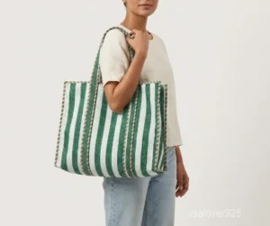Close-up of the green botanical print detailing, exterior horizontal quilting stitching rows, playful cotton tassels, and supportive 5.5-inch gusset base on an Indian cotton tote bag.