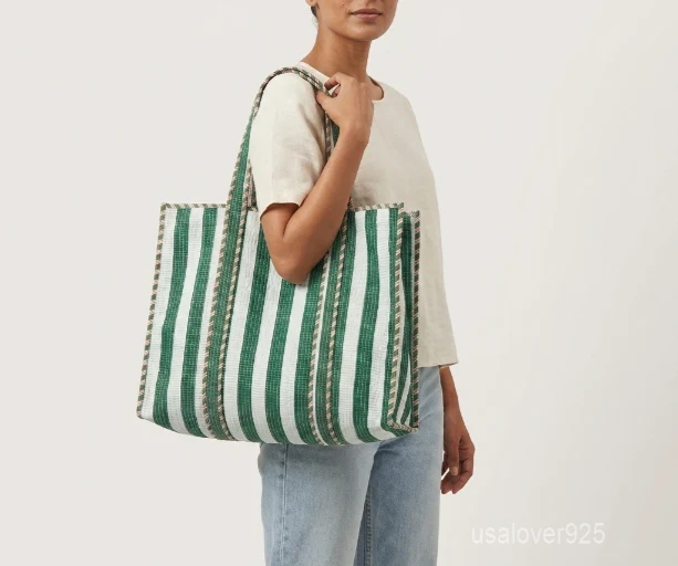 Close-up of the green botanical print detailing, exterior horizontal quilting stitching rows, playful cotton tassels, and supportive 5.5-inch gusset base on an Indian cotton tote bag.