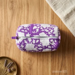 Close-up of the handcrafted traditional purple print detailing, dense horizontal quilted stitching rows, waterproof internal plastic inner lining, elegant beads, and handcrafted tassel on an Indian cotton cosmetic pouch caddy.