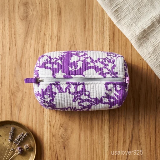 Close-up of the handcrafted traditional purple print detailing, dense horizontal quilted stitching rows, waterproof internal plastic inner lining, elegant beads, and handcrafted tassel on an Indian cotton cosmetic pouch caddy.