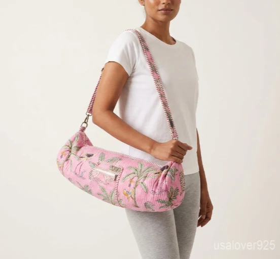Close-up of the handcrafted pink block print detailing, dense quilted stitching tracks, heavy-duty metal clasps, and adjustable crossbody strap on an Indian cotton fitness mat bag.