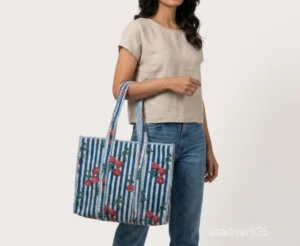 Close-up of the botanical hand block print detailing, dense parallel line quilted stitching rows, deep 7-inch gusset base, and comfortable shoulder handles on an Indian cotton tote bag.