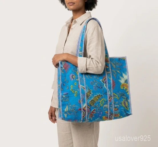 Close-up of the hand block floral prints, dense parallel line quilted stitching, and roomy side gusset on an Indian cotton shopper bag.