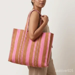 Close-up of the handcrafted pink and brown stripe detailing, dense quilted stitching texture lines, robust handle strap attachments, and neat inner pocket slot on an Indian cotton carryall tote.