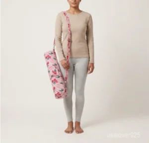 Close-up of the handcrafted coral pink floral block print detailing, dense quilted stitching texture lines, robust adjustable metal strap attachments, and clean zip track on an Indian cotton Pilates carrier bag.