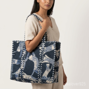 Close-up of the handcrafted indigo blue cat block print detailing, dense quilted stitching texture lines, robust handle attachments, and neatly tailored edges on an Indian cotton carryall tote.