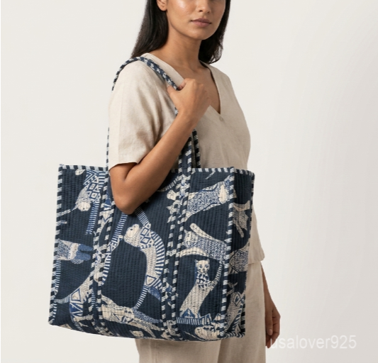 Close-up of the handcrafted indigo blue cat block print detailing, dense quilted stitching texture lines, robust handle attachments, and neatly tailored edges on an Indian cotton carryall tote.