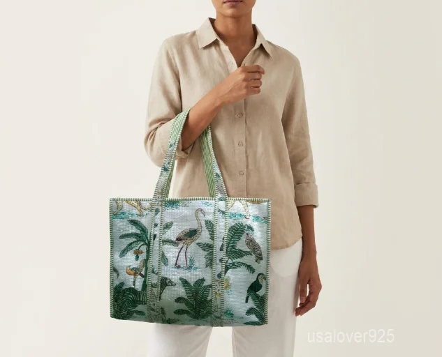 Close-up of the regional hand block print detailing, dense parallel line quilted stitching rows, deep 7-inch bottom gusset base, and comfortable shoulder handles on an Indian cotton tote bag.