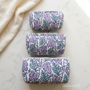 Close-up of the handcrafted multicolor print detailing, dense horizontal quilted stitching rows, waterproof internal plastic lining, elegant beads, and handcrafted tassel on an Indian cotton cosmetic pouch caddy.
