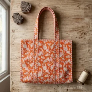 A person carrying a large Orange Floral Quilted Cotton Tote Bag comfortably over their shoulder during a sunny weekend travel trip.