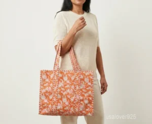 Close-up of the pink floral block print detailing, dense parallel line quilted stitching rows, soft cotton interior lining, and comfortable shoulder handles on an Indian cotton tote bag.