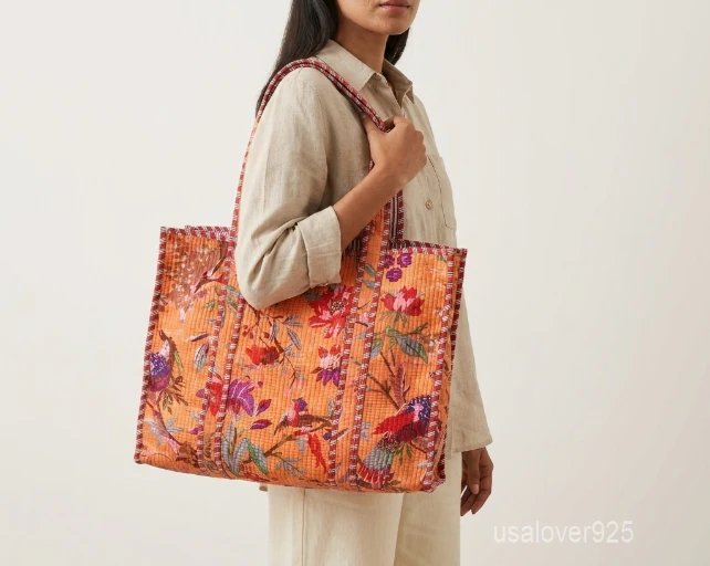 Close-up of the orange block print detailing, dense parallel line quilted stitching rows, and comfortable 13-inch shoulder handles on an Indian cotton tote bag.