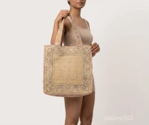 Close-up of the dense Kantha running stitching patterns, soft fabric texture, and reinforced double handles on a red cotton shopper bag.
