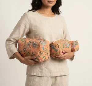 A three-piece nesting set of Peach Floral Quilted Cosmetic Bag Set neatly arranged on a clean vanity counter showing the large, medium, and small size configurations.