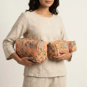 A three-piece nesting set of Peach Floral Quilted Cosmetic Bag Set neatly arranged on a clean vanity counter showing the large, medium, and small size configurations.