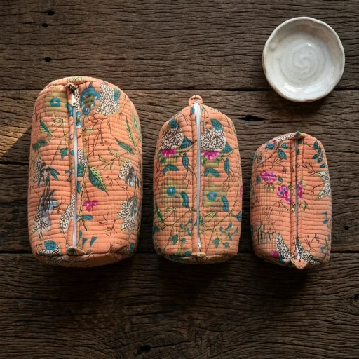 Close-up of the handcrafted peach floral print detailing, dense horizontal quilted stitching rows, waterproof internal lining, elegant beads, and handcrafted tassel on an Indian cotton cosmetic pouch caddy.