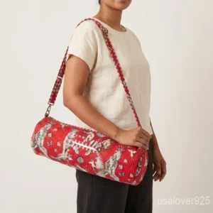 Close-up of the handcrafted red block print detailing, dense diamond quilted stitching rows, heavy-duty zipper slider, and adjustable crossbody strap on an Indian cotton fitness mat bag.