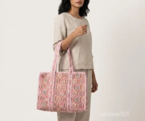 Close-up of the pink botanical floral print, dense parallel line quilted stitching rows, and comfortable reinforced striped handles on an Indian cotton shopper bag.