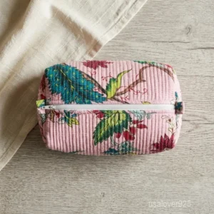Close-up of the handcrafted tropical print detailing, dense horizontal quilted stitching rows, waterproof internal plastic lining, elegant beads, and handcrafted tassel on an Indian cotton cosmetic pouch caddy.
