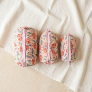 A traveler organizing the Pink Floral Makeup Pouch Set on a bathroom vanity counter, displaying its multi-size versatility and bohemian aesthetic travel style.