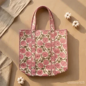 Woman walking through an outdoor market carrying a Pink Floral Hand Block Print Quilted Cotton Tote Bag loaded with books.