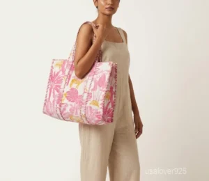 Close-up of the pink floral block print detailing, dense parallel line quilted stitching rows, square profile layout, and comfortable handles on an Indian cotton tote bag.