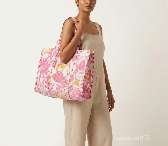 Close-up of the pink floral block print detailing, dense parallel line quilted stitching rows, square profile layout, and comfortable handles on an Indian cotton tote bag.