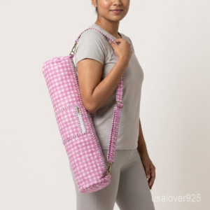 An active practitioner carrying the Pink Gingham Yoga Mat Carrier over the shoulder while commuting, displaying its comfortable fit and vibrant studio-ready look.
