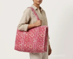 Close-up of the pink botanical floral print detailing, dense parallel line quilted stitching rows, and comfortable 12-inch shoulder handles on an Indian cotton tote bag.