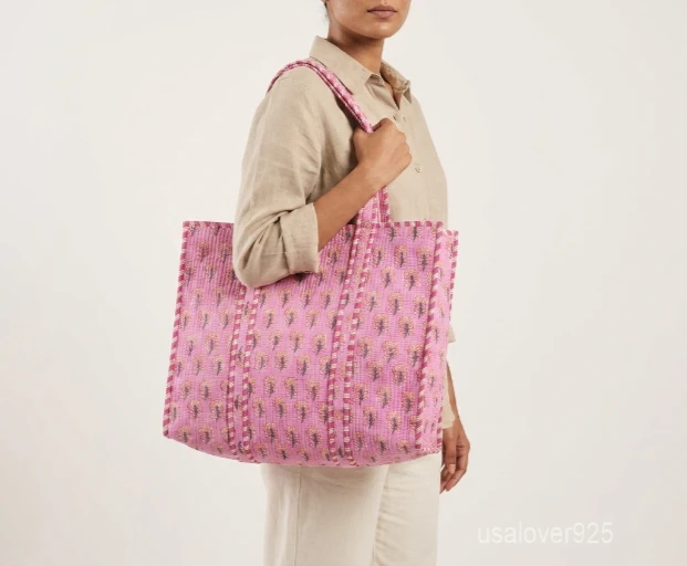 Close-up of the pink botanical floral print detailing, dense parallel line quilted stitching rows, and comfortable 13-inch shoulder handles on an Indian cotton tote bag.