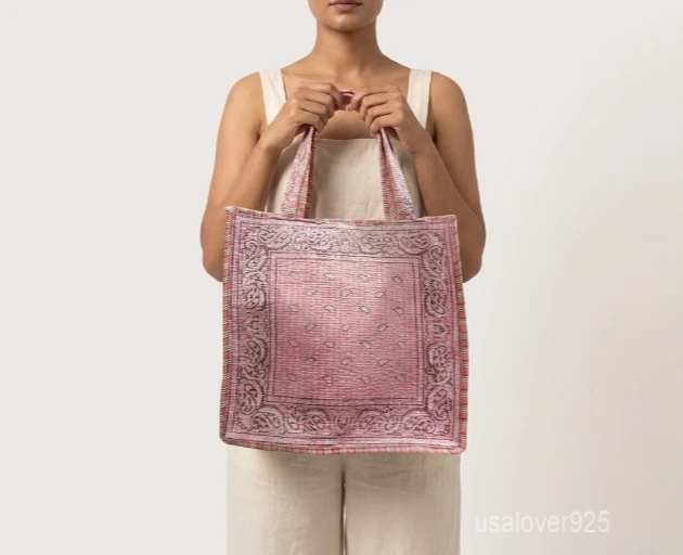 Close-up of the pink paisley bandana pattern, dense Kantha-style parallel running stitches, and comfortable double-strap handles on an Indian cotton shopper bag.