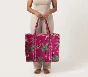 Close-up of the handcrafted pink block print detailing, solid back panel pattern, dense quilted stitching texture lines, robust handle attachments, and convenient inner pocket on an Indian cotton carryall tote.